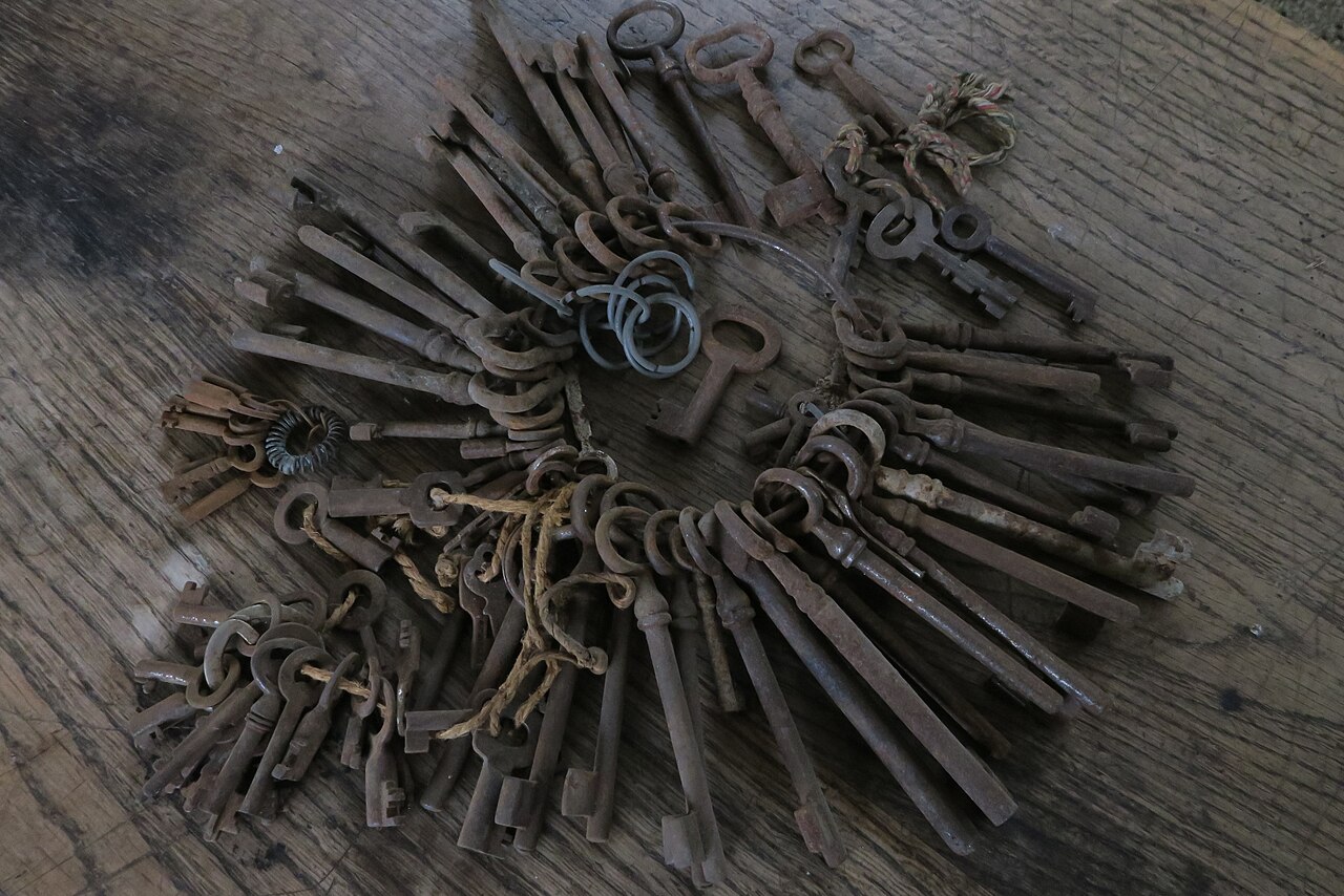 Several bunches of rusty keys spread across a wooden surface.