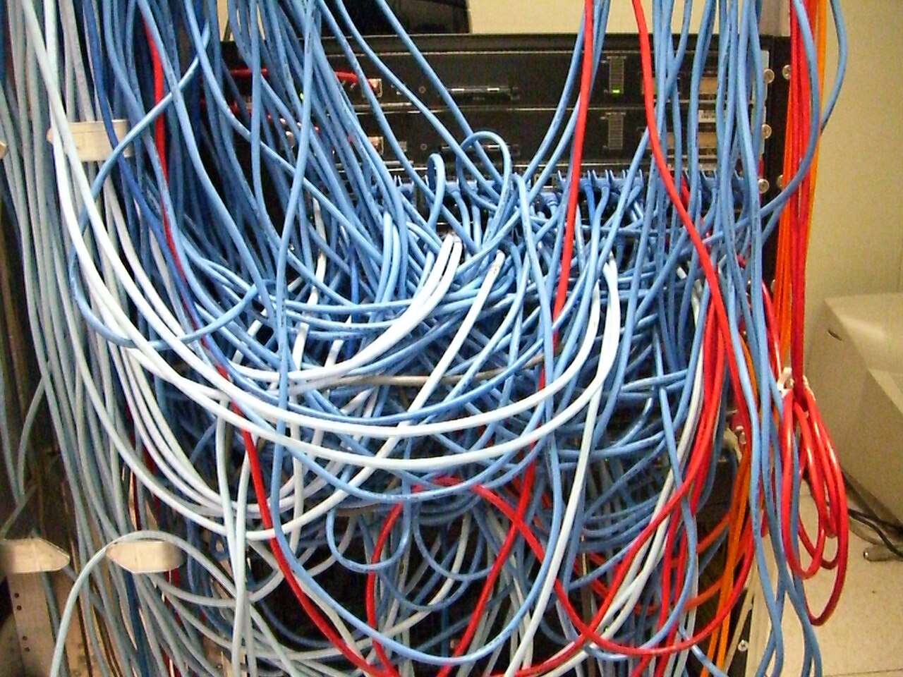 A server rack with rows of network equipment and connected cables.
