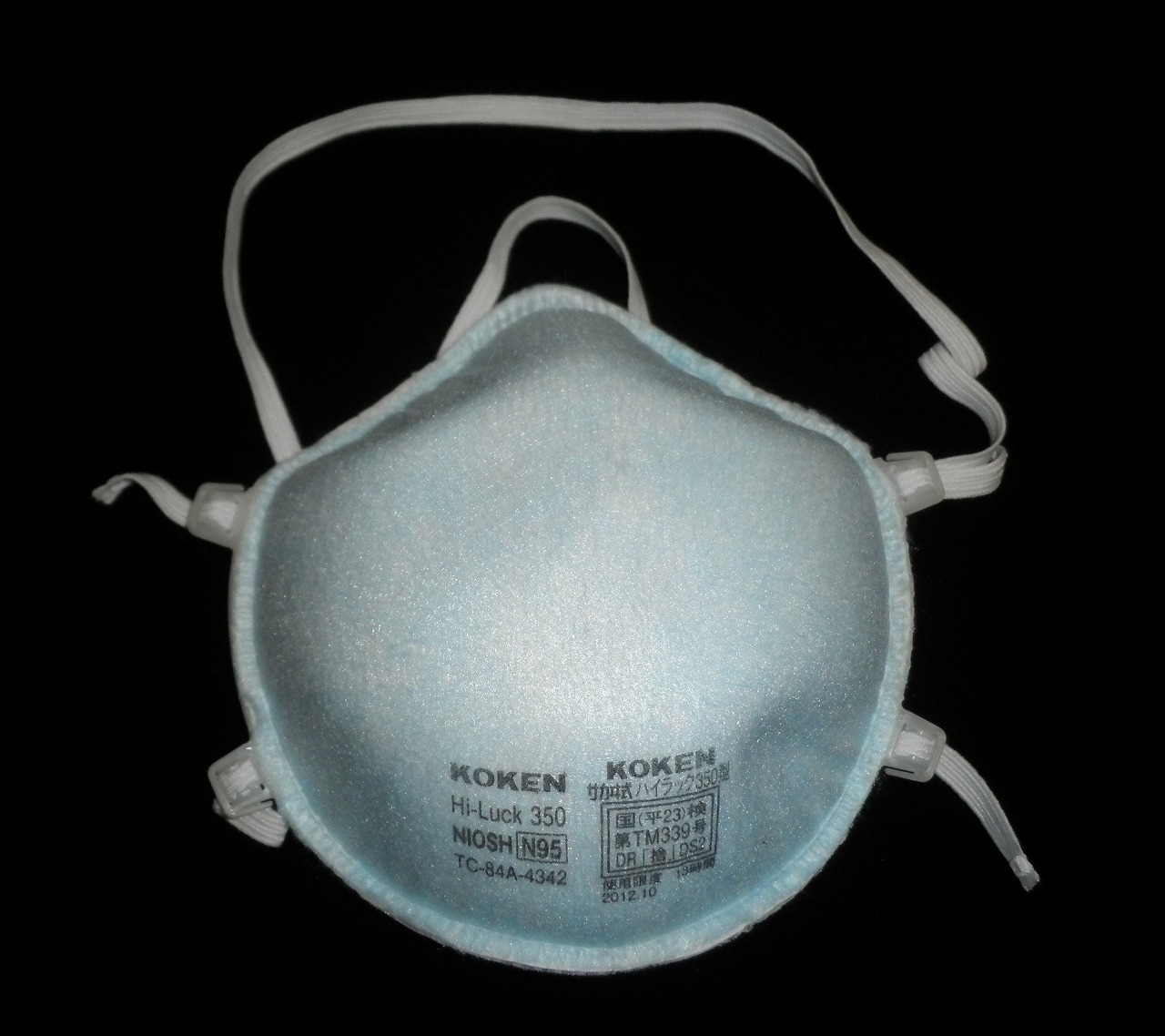 An N95 respirator with its straps spread out on a dark background.