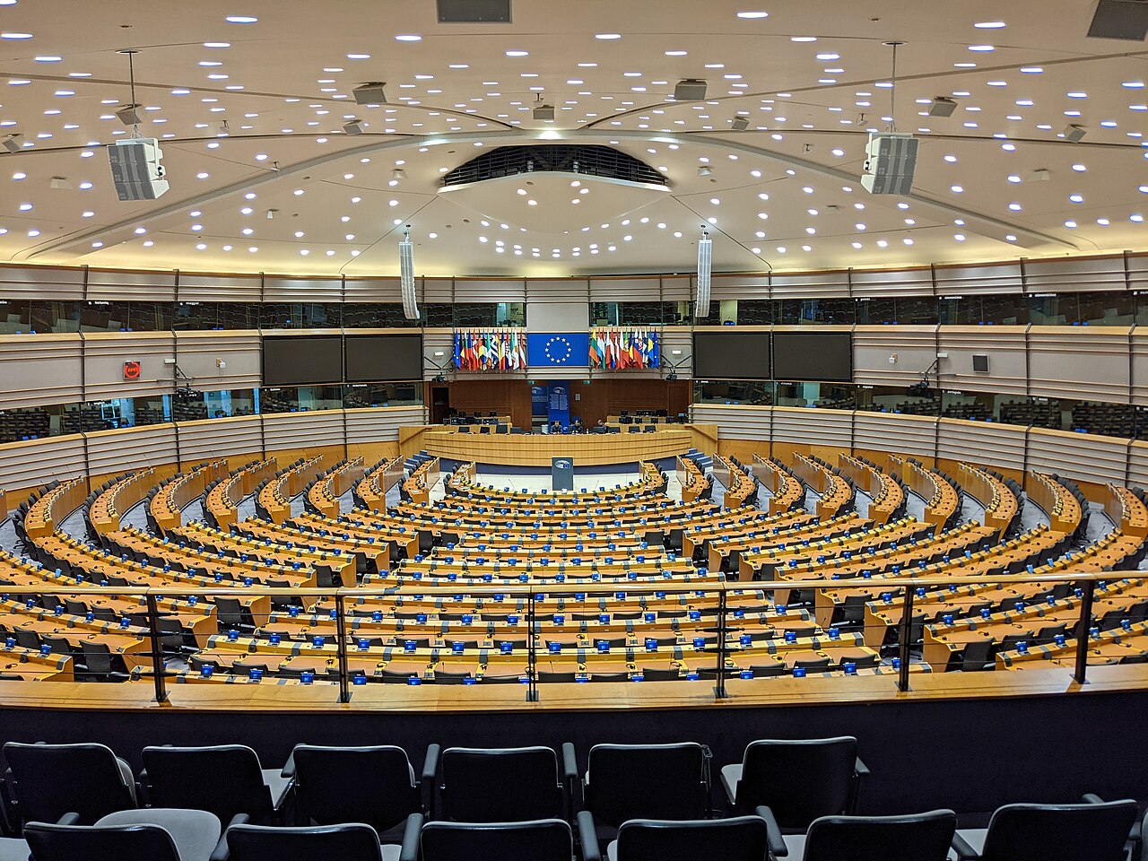 The empty European Parliament chamber in Brussels, with curved rows of seats.