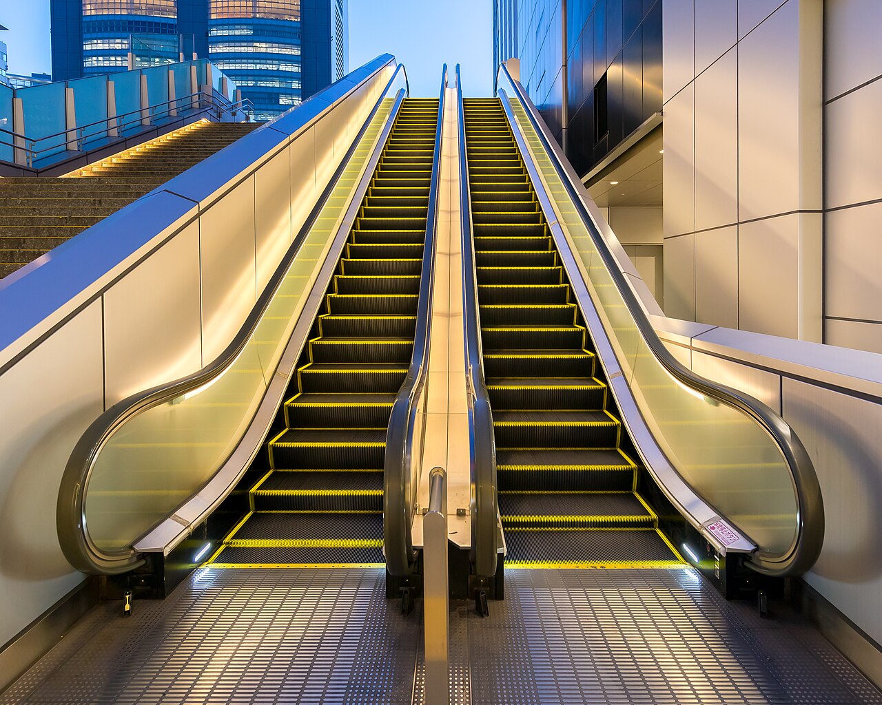 An empty escalator in Shinjuku, Tokyo, with blue side panels and yellow-edged steps.