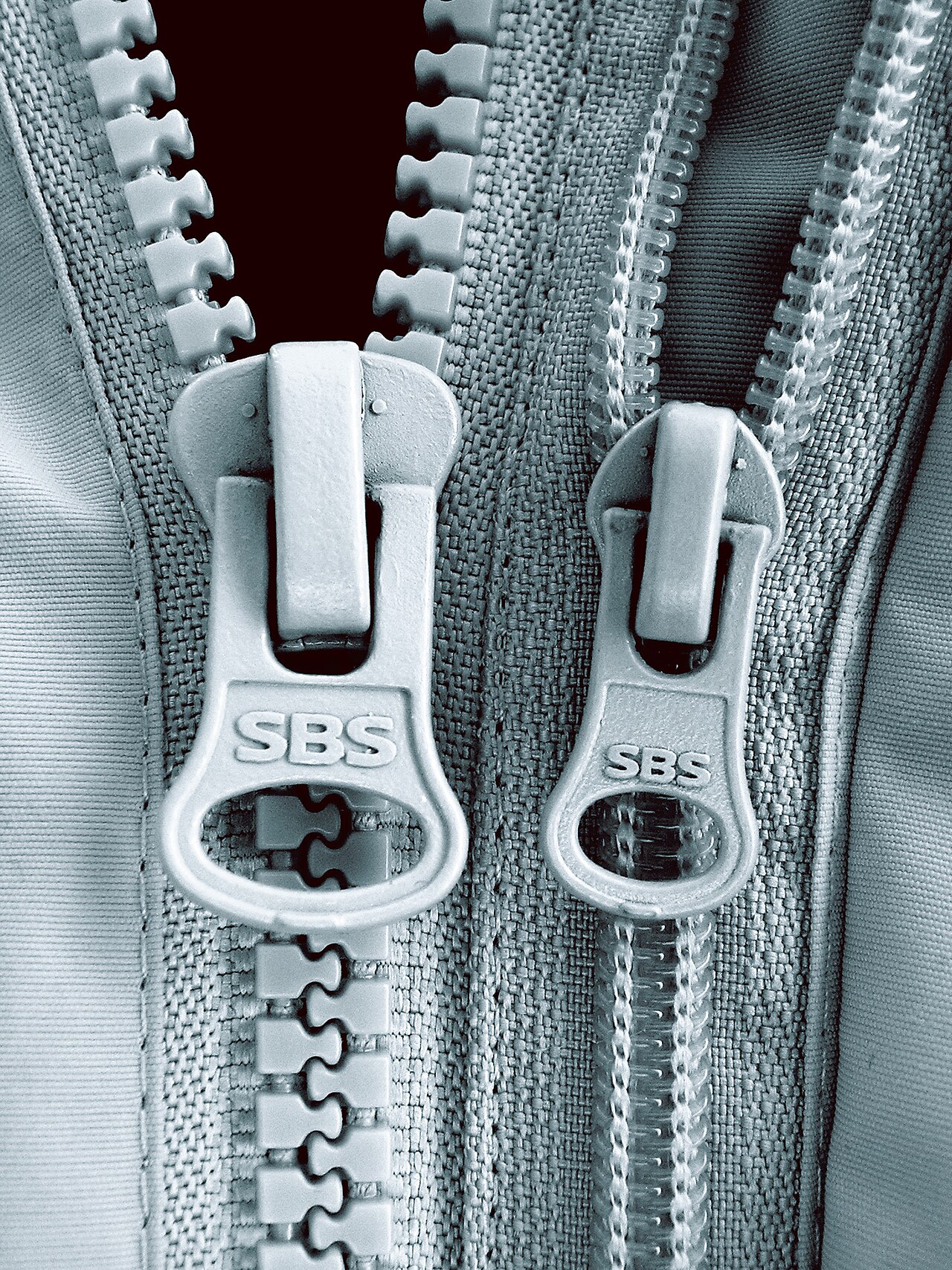 Two partly open zips showing the separated teeth above each slider and joined rows below.