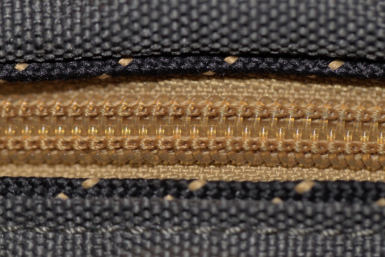 A close-up of the interlocking elements of a gold-coloured zip.